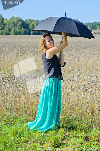 Image of Portrait of woman with umbrella in field