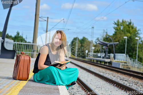 Image of Woman sitting on the station and reading