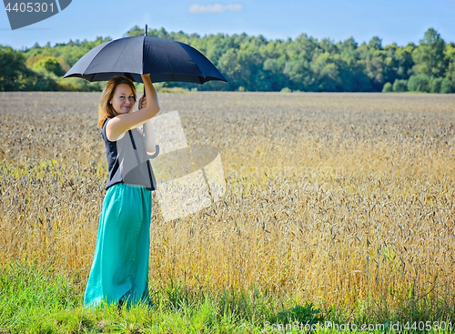 Image of Portrait of woman with umbrella in field