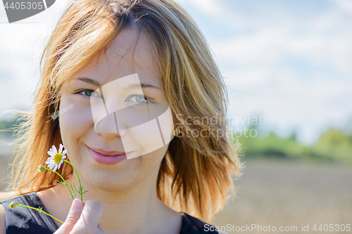 Image of Portrait of young female with camomile