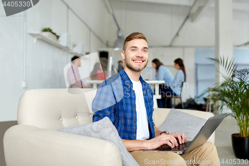 Image of smiling man with laptop working at office