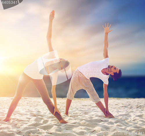 Image of couple making yoga exercises on beach