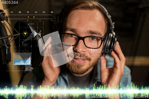 Image of man with headphones singing at recording studio