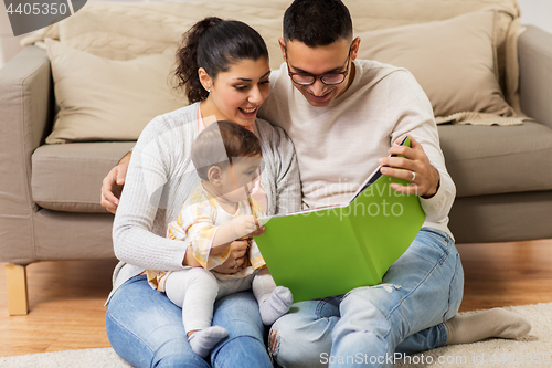 Image of happy family with baby reading book at home