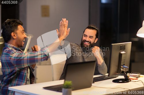 Image of creative team making high five at night office