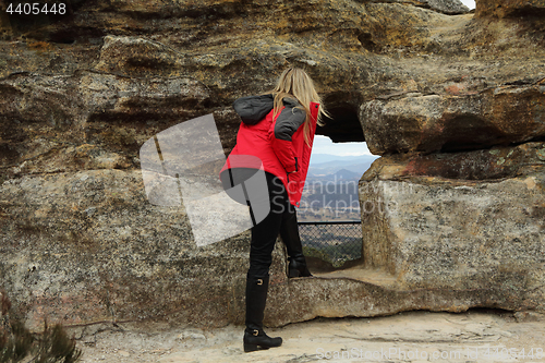 Image of A woman looking through the cave opeing with views over a valley