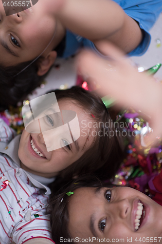Image of kids  blowing confetti while lying on the floor