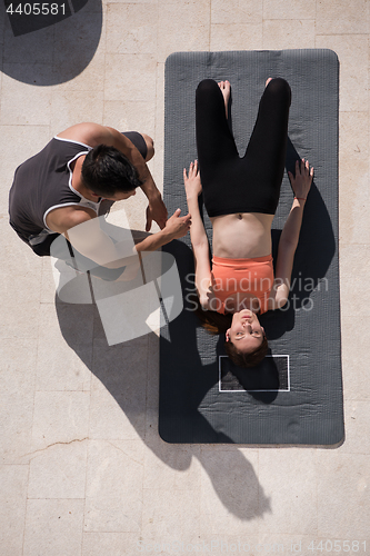 Image of woman with personal trainer doing morning yoga exercises top vie