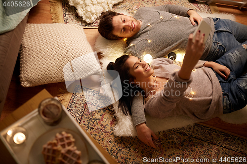 Image of couple lying on floor and making selfie at home