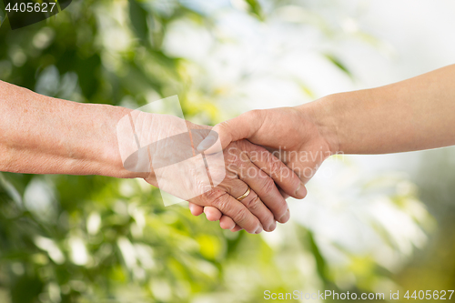 Image of close up of senior and young woman holding hands