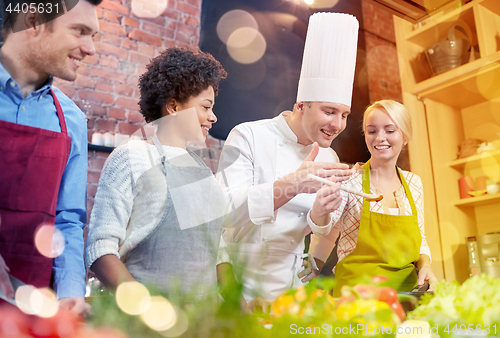 Image of happy friends and chef cook cooking in kitchen