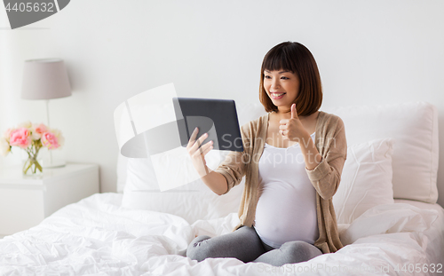 Image of happy pregnant asian woman with tablet pc at home