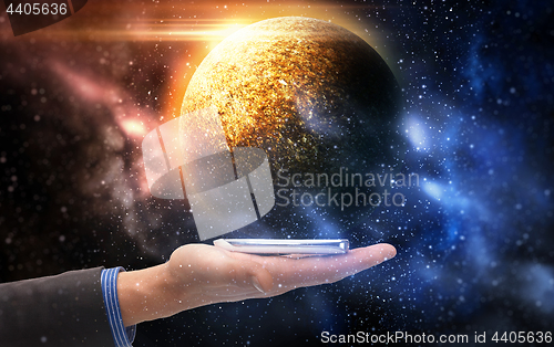 Image of hand holding smartphone over planet in space