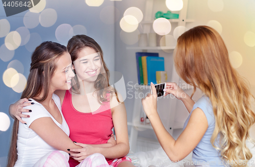 Image of teen girls with smartphone taking picture at home