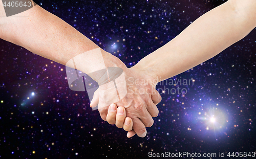 Image of close up of senior and young woman holding hands