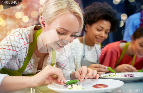 Image of happy women cooking and decorating dishes