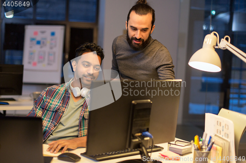 Image of creative team with computer working late at office