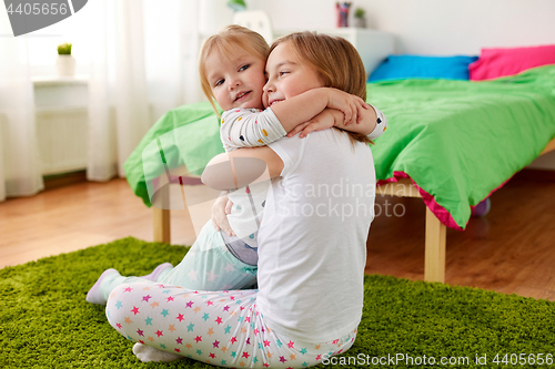 Image of happy little girls or sisters hugging at home