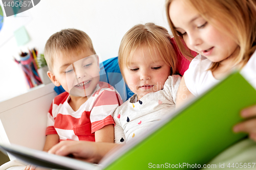 Image of little kids reading book in bed at home