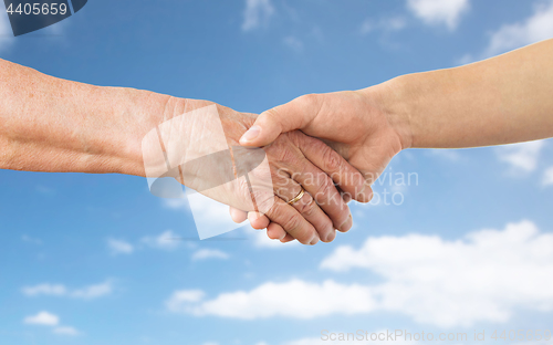 Image of close up of senior and young woman hands over sky