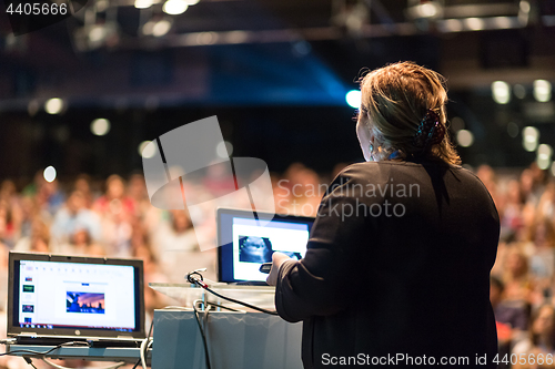 Image of Female public speaker giving talk at Business Event.