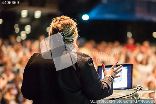 Image of Female public speaker giving talk at Business Event.