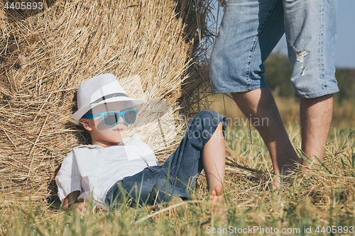 Image of Father and son sitting in the park at the day time.