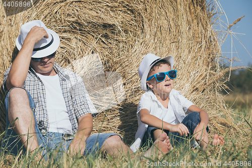 Image of Father and son sitting in the park at the day time.