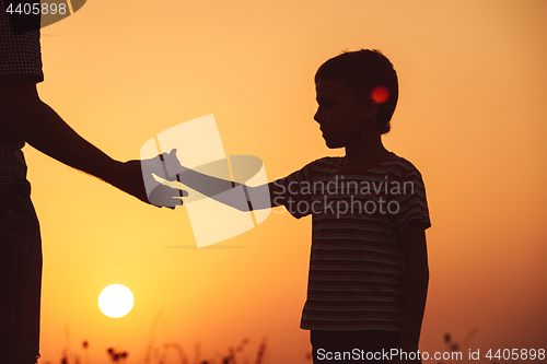 Image of Father and son playing in the park at the sunset time.