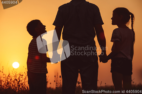 Image of Father and children standing in the park at the sunset time. 