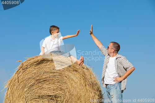 Image of Father and son standing in the park at the day time.