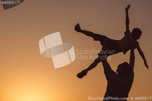 Image of Father and son playing in the park at the sunset time.