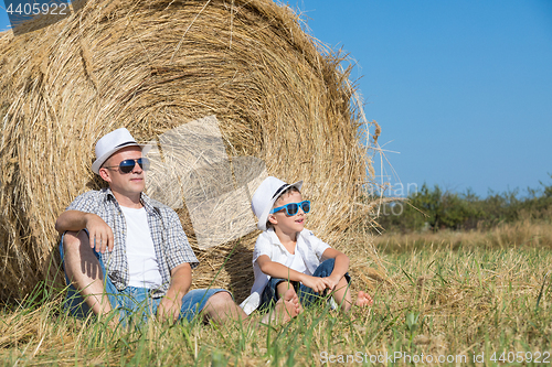 Image of Father and son sitting in the park at the day time.