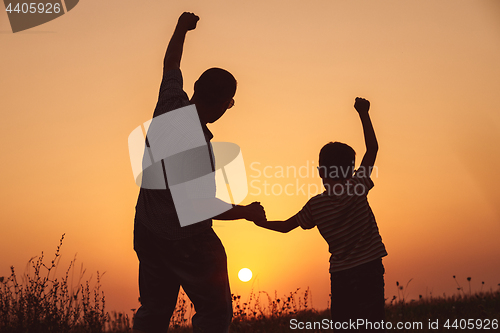 Image of Father and son playing in the park at the sunset time.