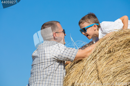 Image of Father and son standing in the park at the day time.