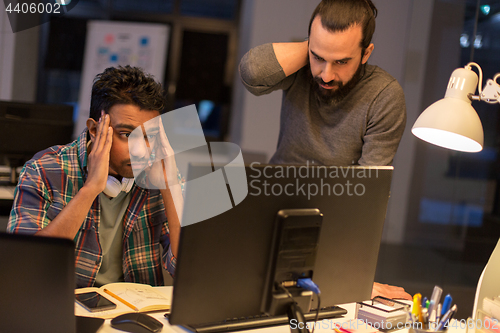 Image of creative team with computer working late at office