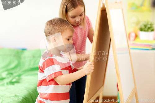 Image of happy kids drawing on chalk board at home