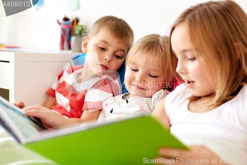 Image of little kids reading book in bed at home