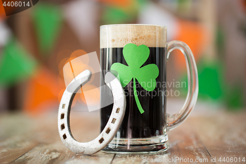 Image of shamrock on glass of beer and horseshoe on table