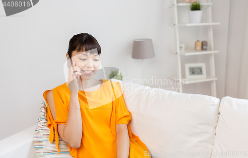 Image of happy asian woman calling on smartphone at home