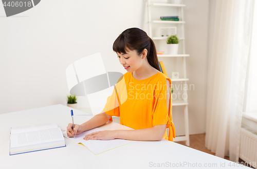 Image of happy student girl with book and notebook at home