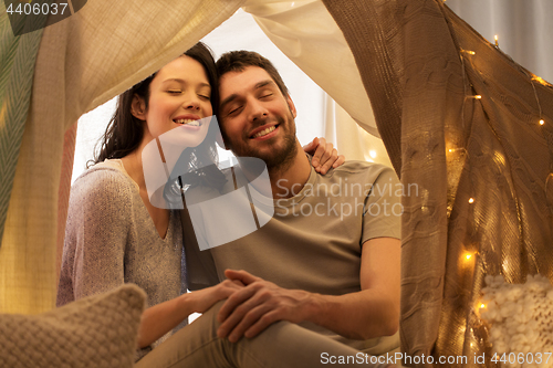 Image of happy couple in kids tent at home