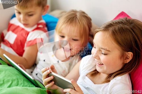 Image of little kids with smartphone in bed at home