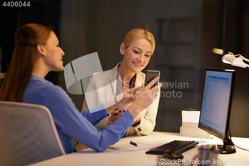 Image of businesswomen with smartphone late at night office