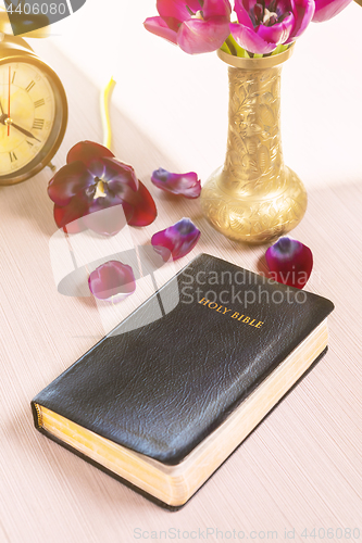 Image of Holy Bible and old gold alarm clock on wood table