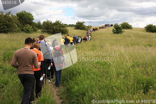 Image of People walking in a line towards the tent on the top mof the hill.