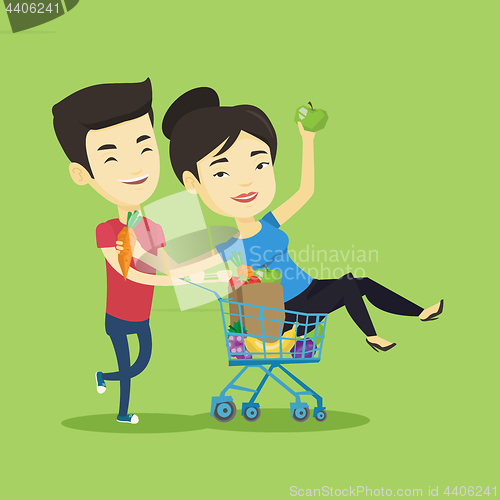 Image of Couple of friends riding by shopping trolley.