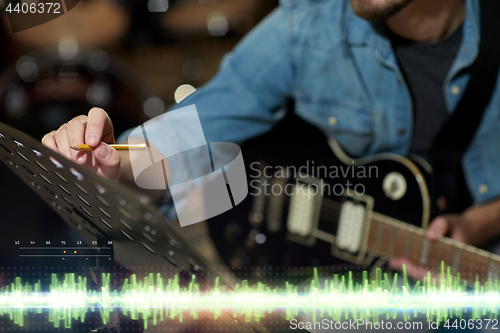 Image of musician with guitar and music book at studio