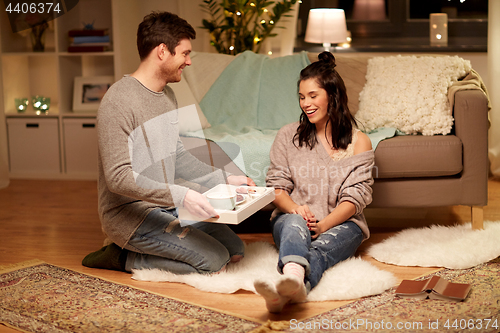 Image of happy couple with food on tray at home