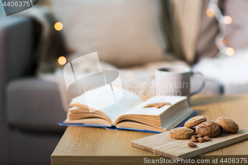 Image of oat cookies, almonds and book on table at home